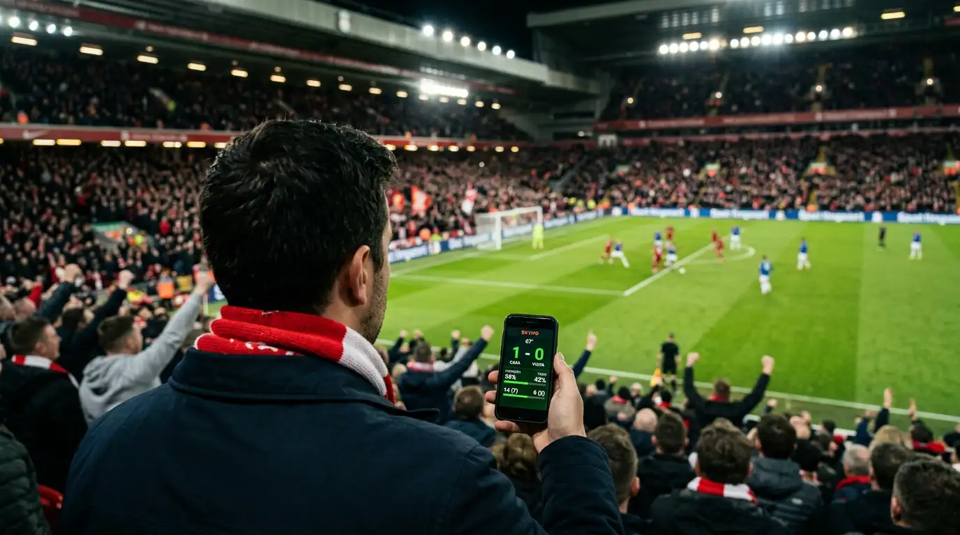 Aficionado en la grada de un estadio de fútbol consultando su teléfono móvil durante un partido