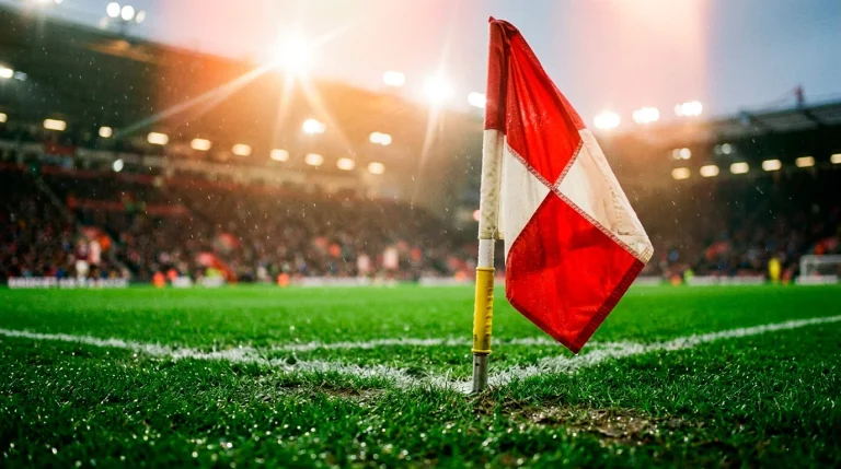 Primer plano de un banderín de córner en un campo de fútbol de la Premier League con el césped mojado bajo los focos