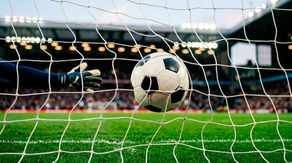 Portería de fútbol en un estadio de la Premier League con un balón acercándose